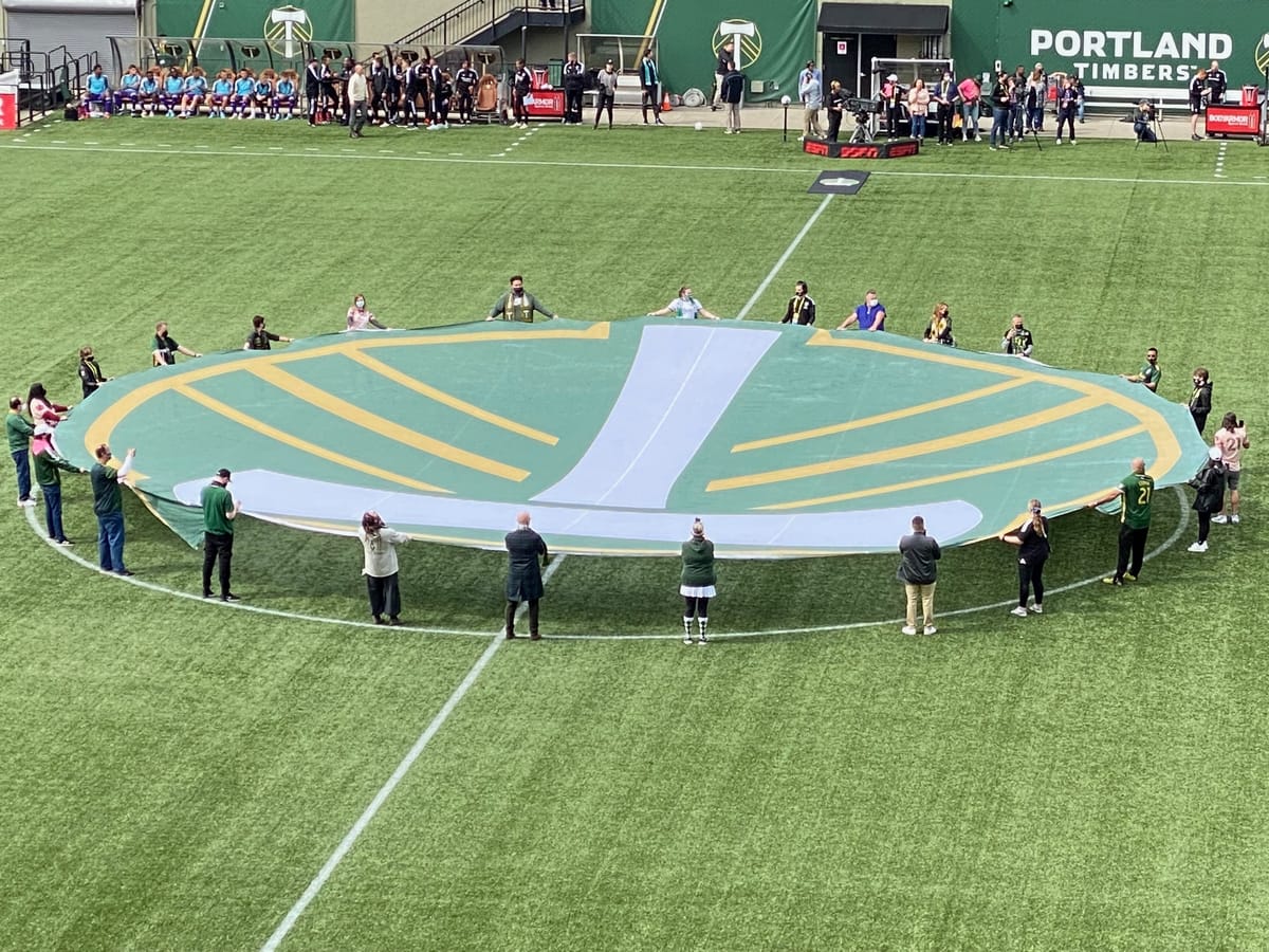 A picture of people holding a giant Portland Timbers flag before a match