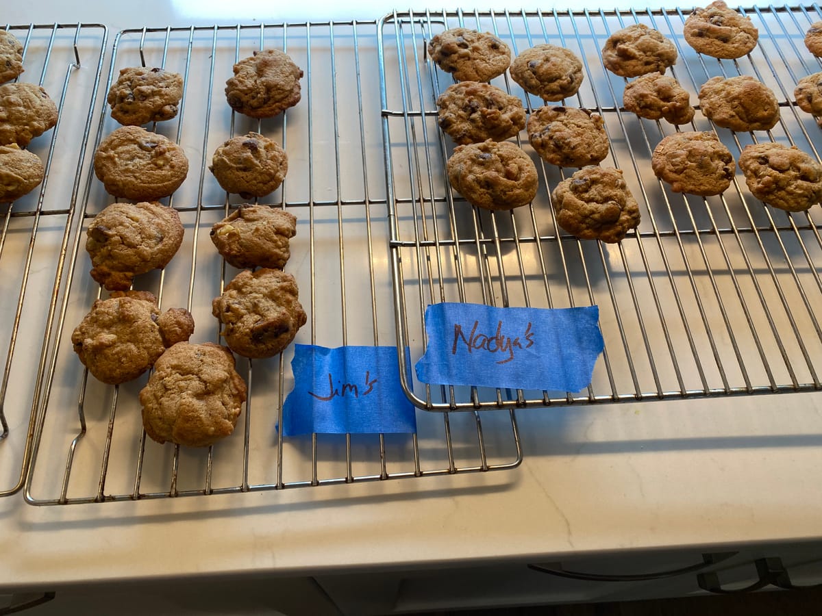 Two racks of chocolate chip cookies marked "Jim's" and "Nadya's" with blue painters tape